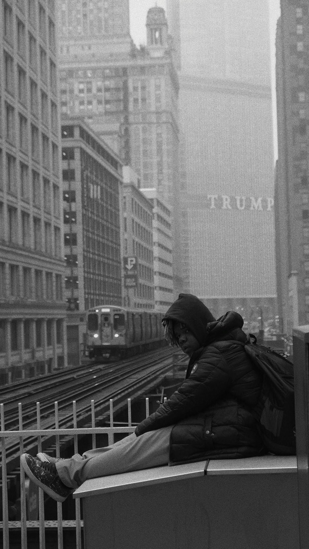 man in black jacket and black cap standing on train rail