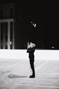 A detective discreetly observing a location through binoculars at dusk.