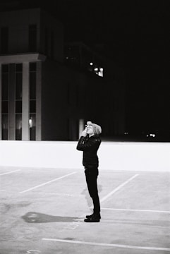 A private investigator observing a subject through binoculars from a parked car.