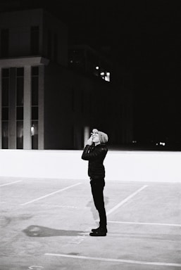 A private detective discreetly observing through binoculars in a cityscape at dusk.