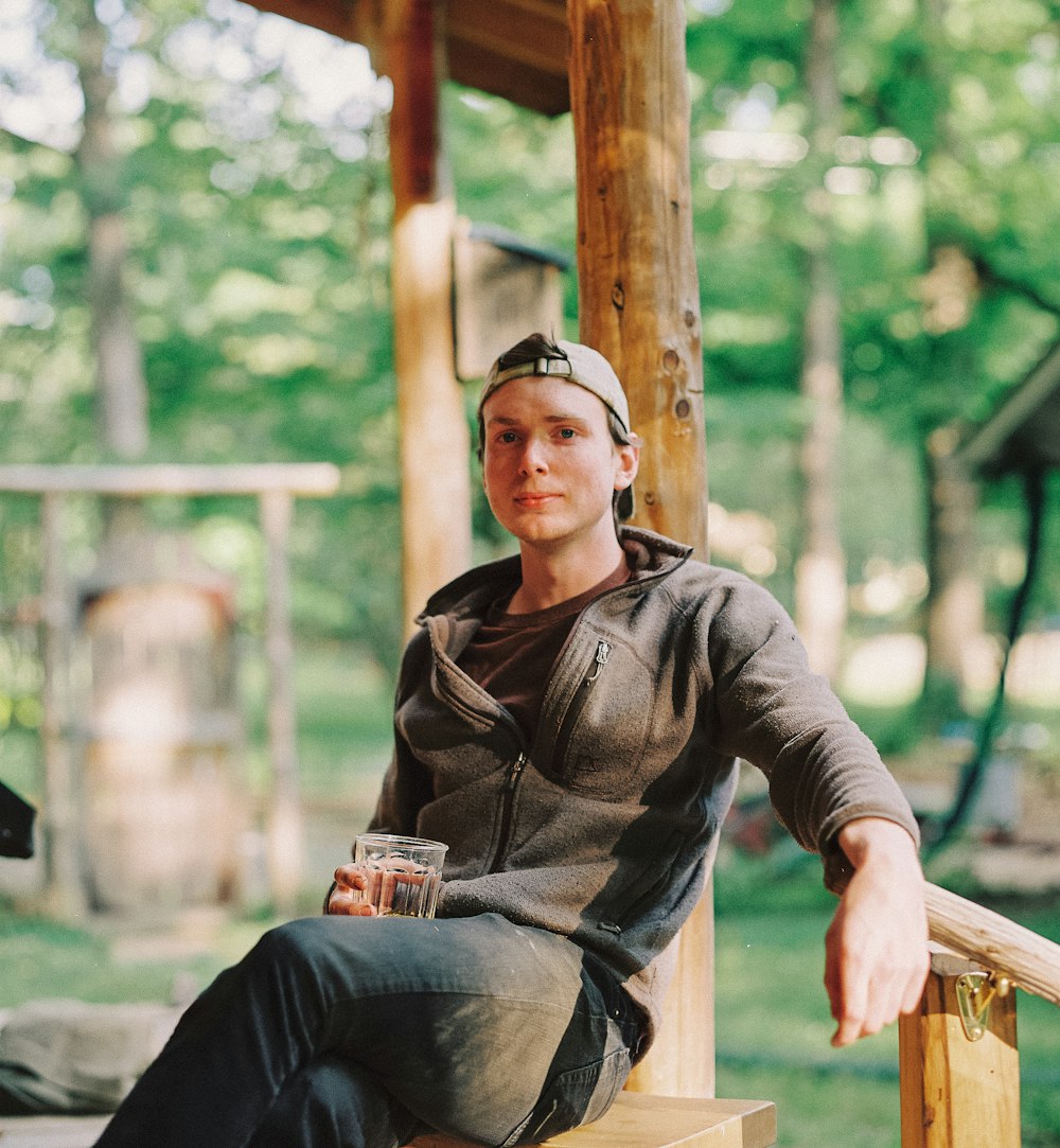 man in brown leather jacket sitting on brown wooden bench