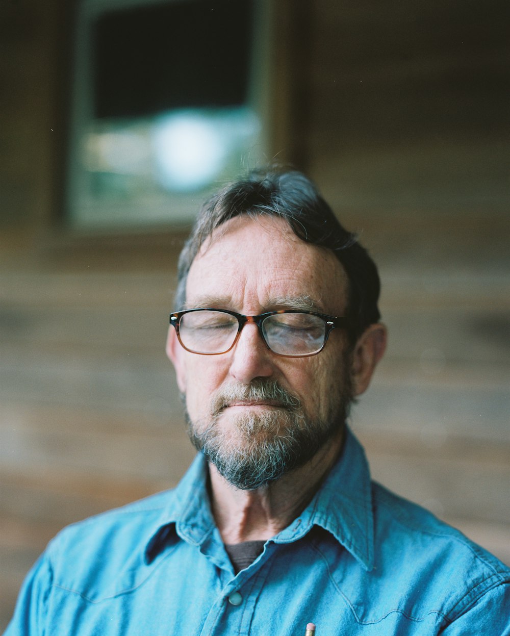 man in blue dress shirt wearing black framed eyeglasses