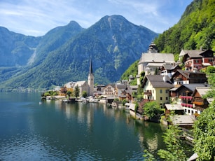 houses near body of water and mountain during daytime