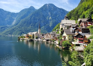 houses near body of water and mountain during daytime