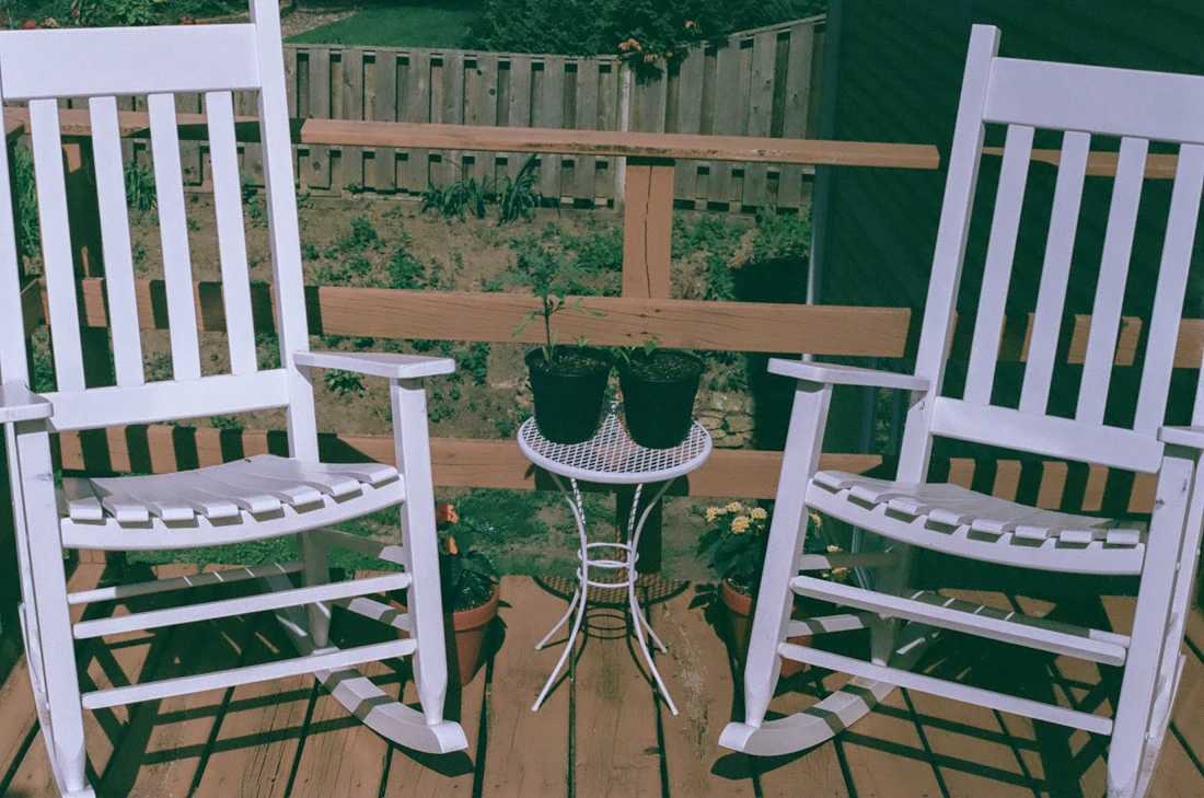White rocking chairs lined up on a porch behind a wood rail