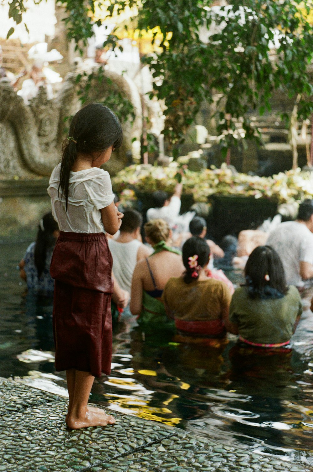 woman in white shirt and red skirt standing on water fountain