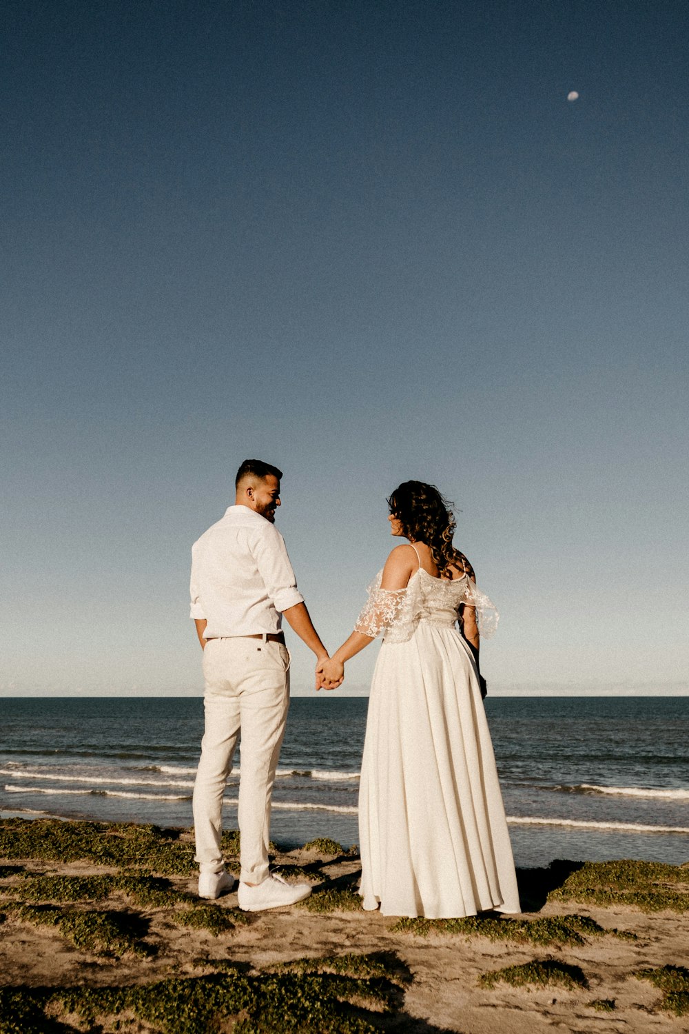 man and woman standing on beach during daytime