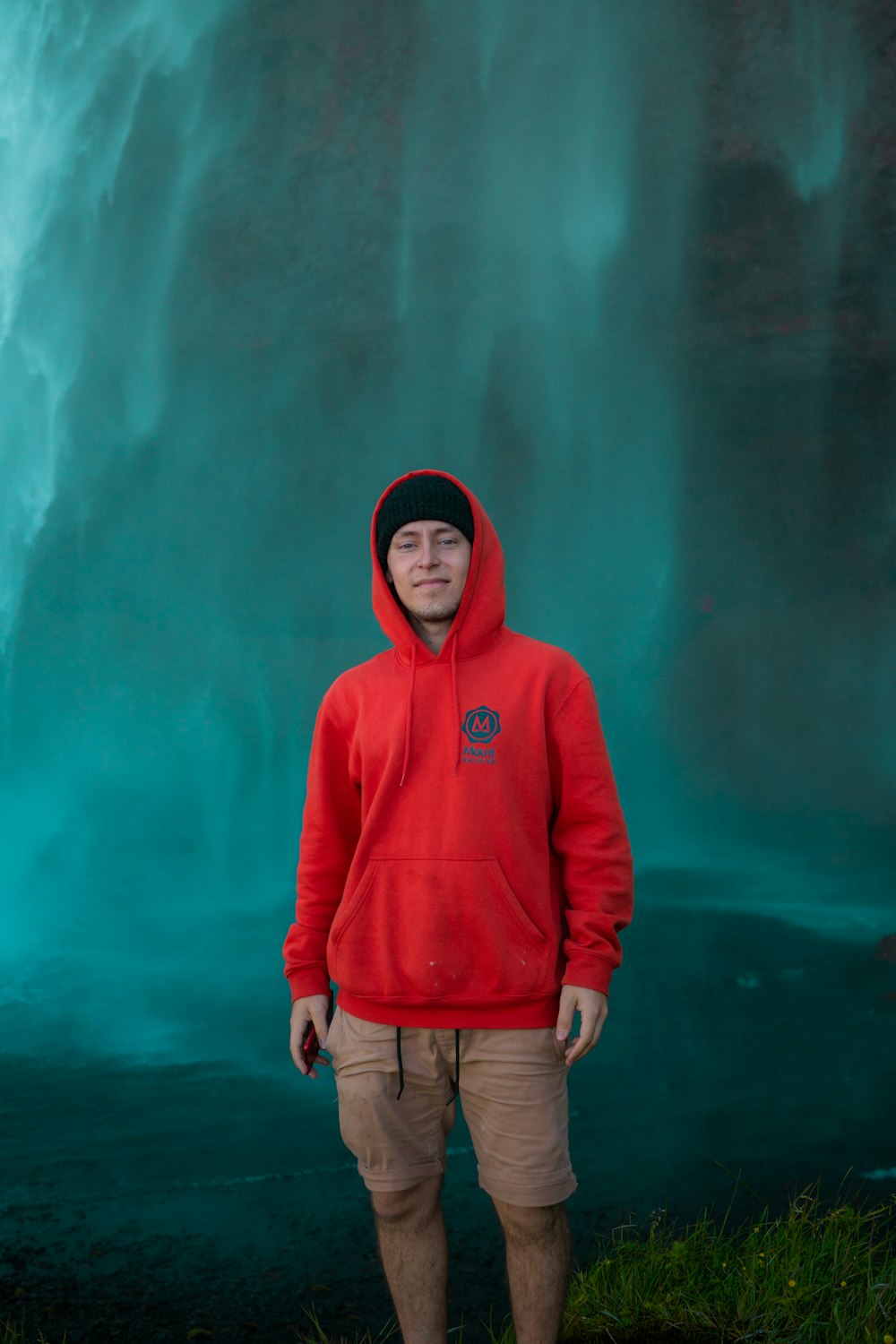 woman in red hoodie standing in front of green wall