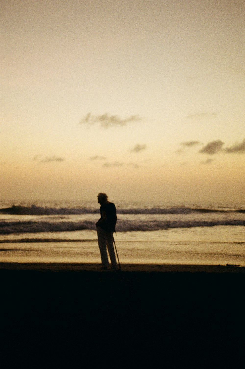 silhouette of person standing on seashore during daytime