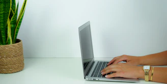 person using macbook pro on white table