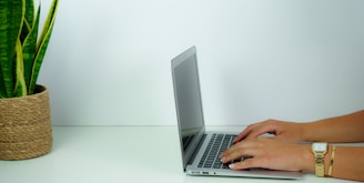 person using macbook pro on white table