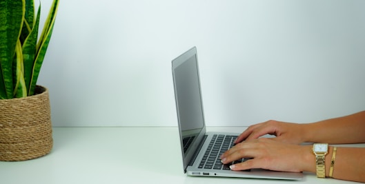 person using macbook pro on white table