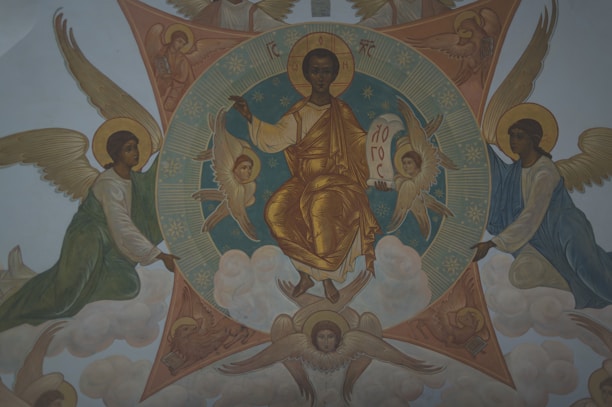 A religious painting featuring a central figure with a golden robe, seated on a cloud, holding a book or scroll. Surrounding the central figure are several winged angels. The background contains geometric shapes and clouds, contributing to a celestial atmosphere.