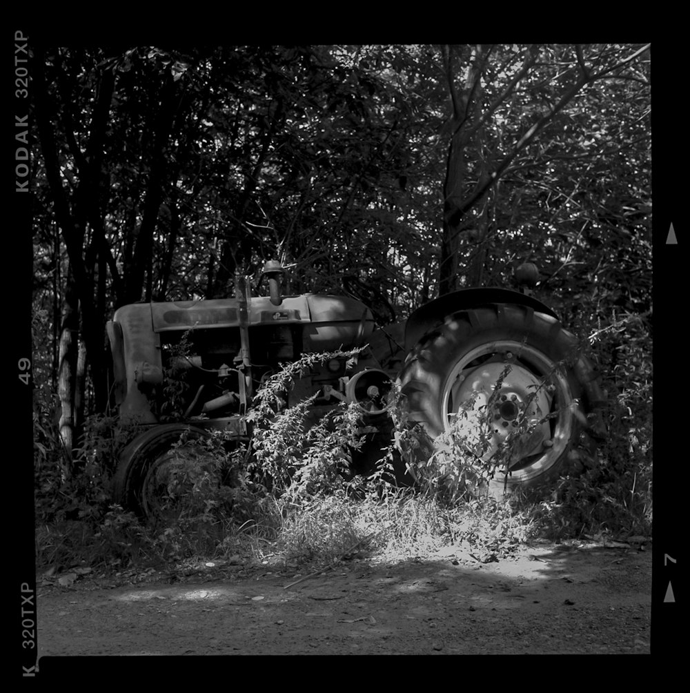 Photo en niveaux de gris d’un tracteur près d’arbres