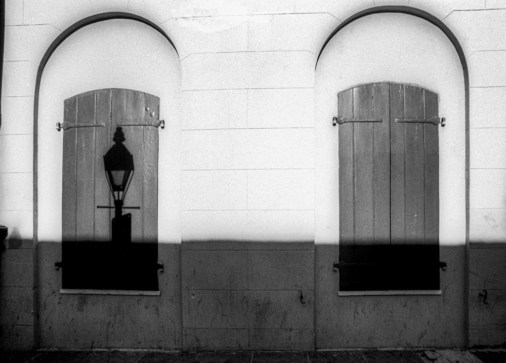 grayscale photo of man standing on window