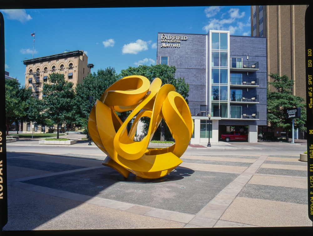 a large yellow sculpture sitting on the side of a road
