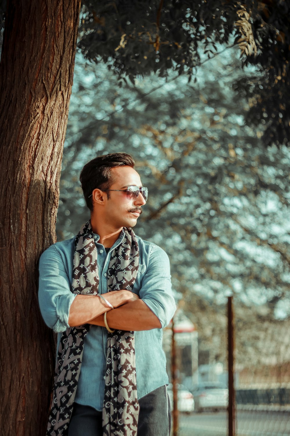 man in blue denim jacket standing beside tree during daytime