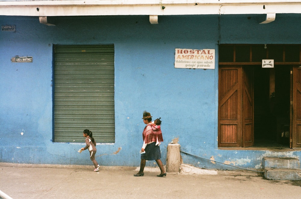 2 boys standing in front of blue and white painted wall during daytime