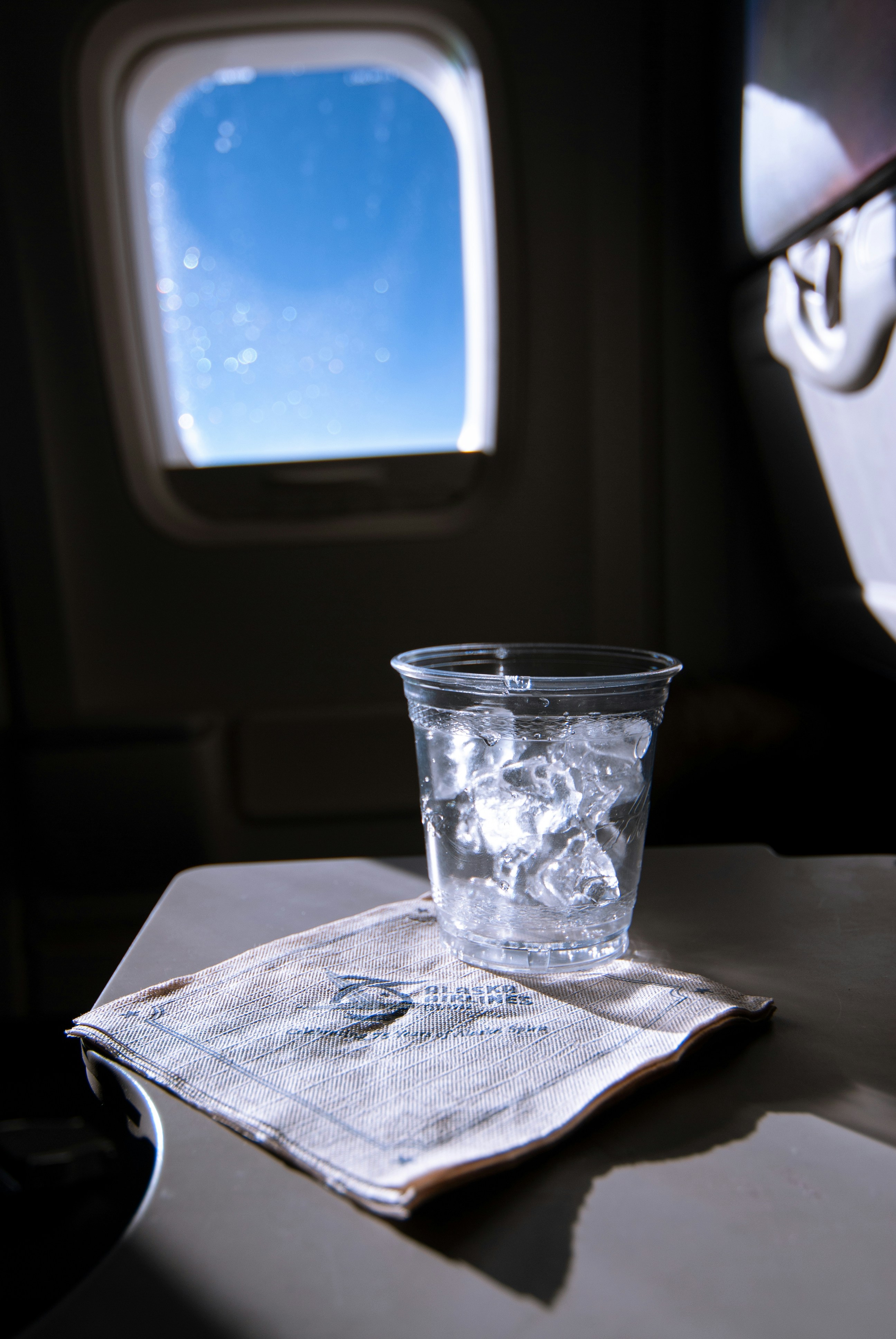 cup of ice water on tray table inside plane