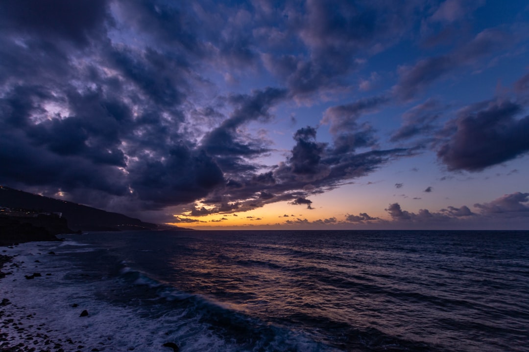 body of water under cloudy sky during sunset