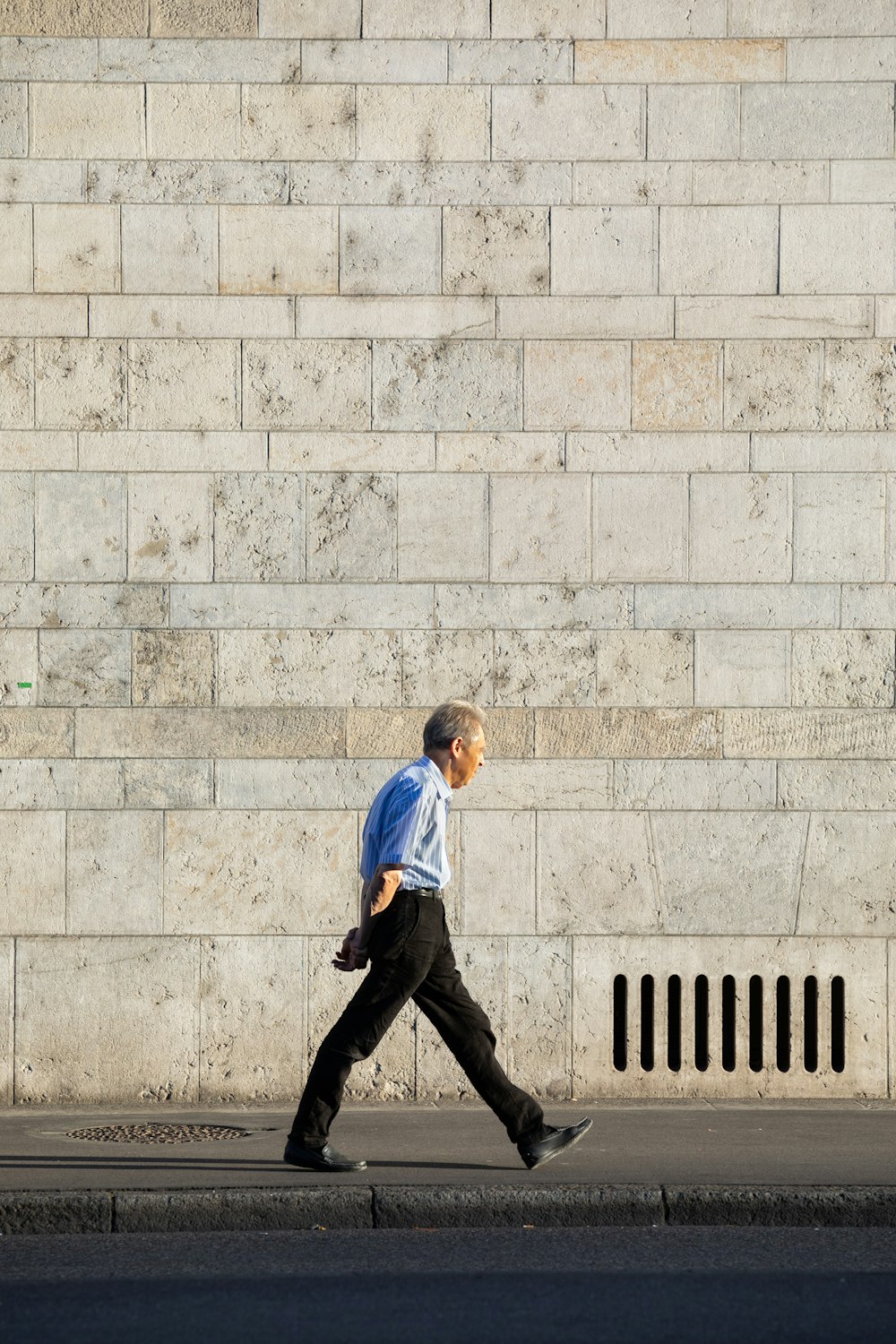 a man walking down the street in front of a wall