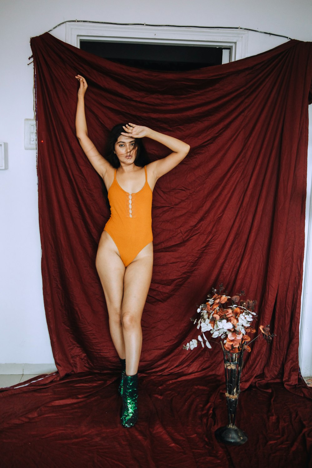 woman in red one piece swimsuit standing on red curtain