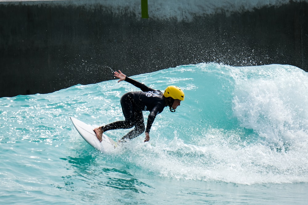 man in black wet suit riding white surfboard during daytime