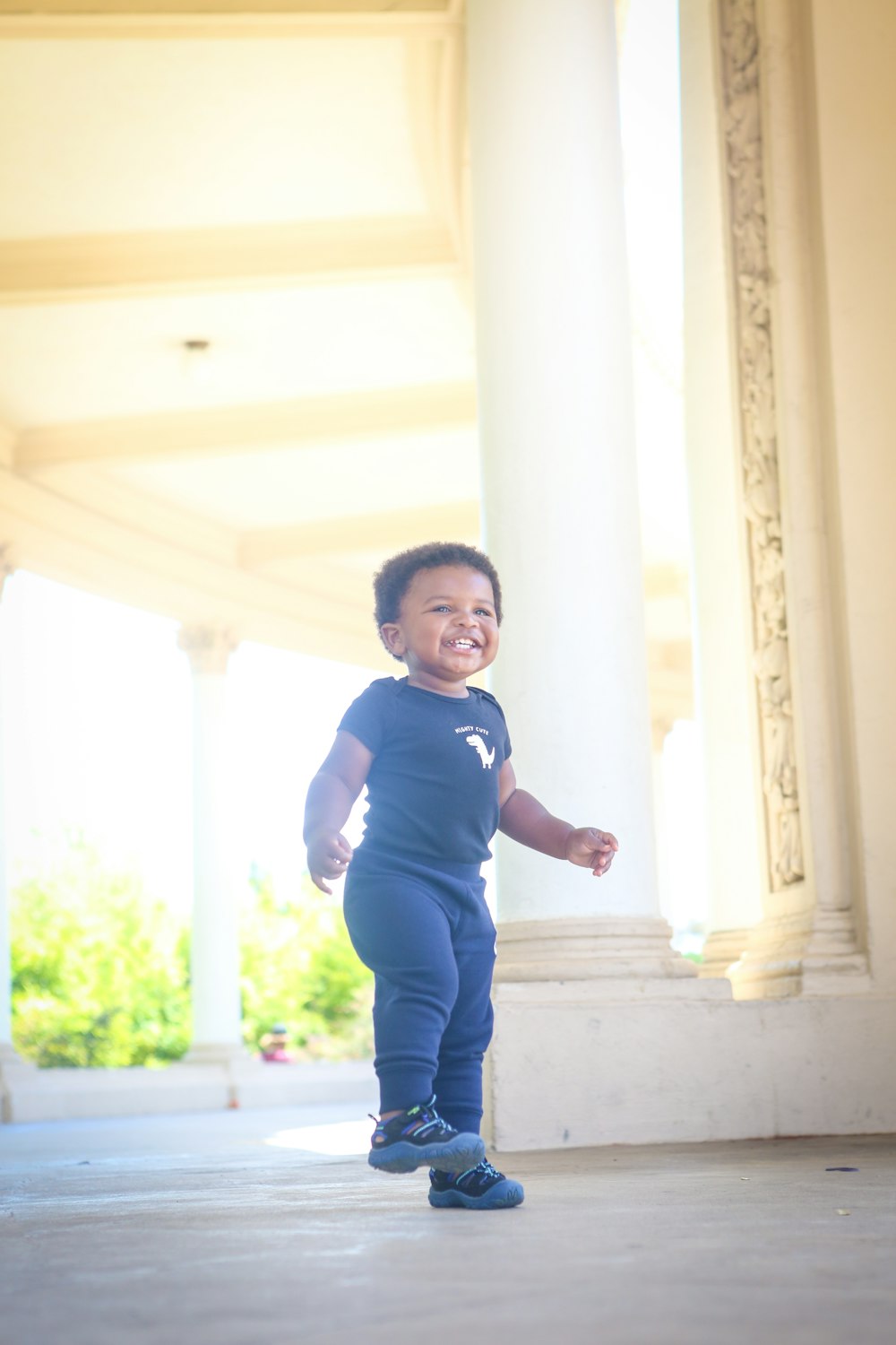 boy in blue and black polo shirt standing near window during daytime