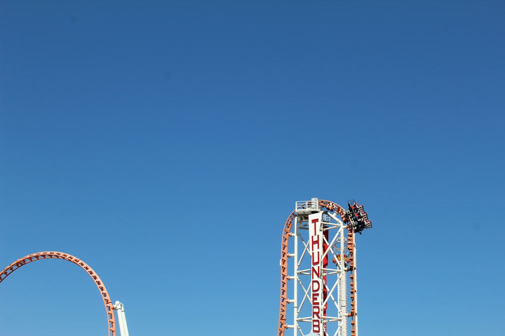 roda gigante vermelha e branca sob o céu azul durante o dia