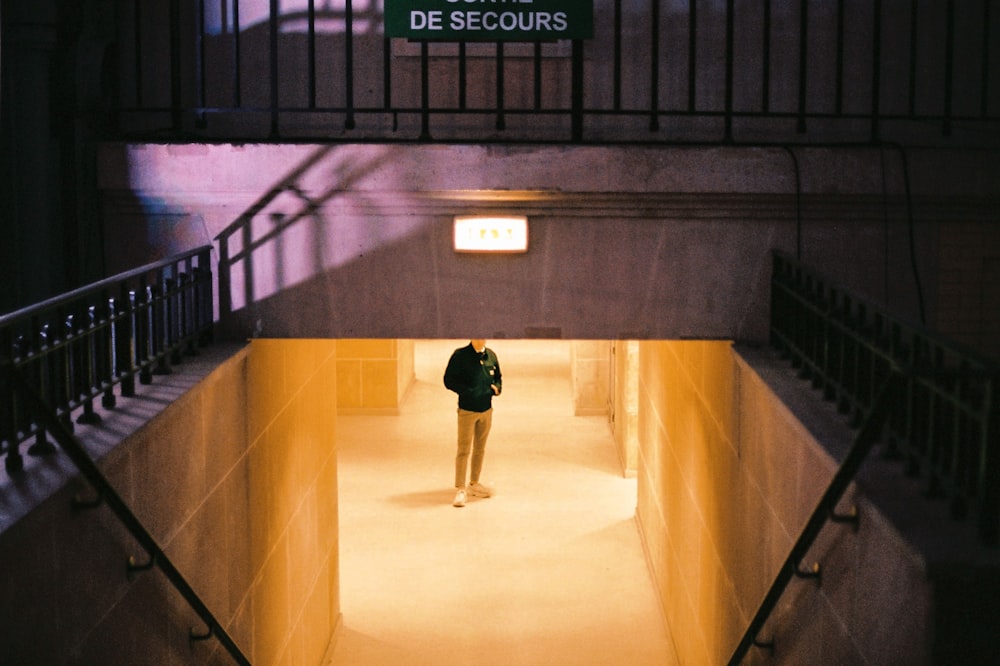 man in black jacket and black pants walking on brown concrete floor