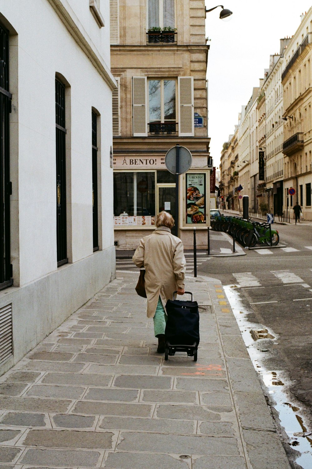 woman in beige coat walking on sidewalk during daytime