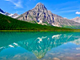 Majestic mountain range reflected perfectly in a calm blue lake at sunrise