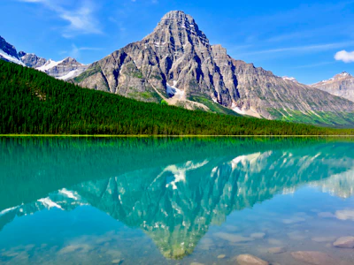 Majestic mountain range reflected perfectly in a calm blue lake at sunrise