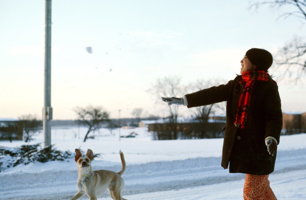 woman in red jacket holding black leather bag standing beside white short coated dog during daytime