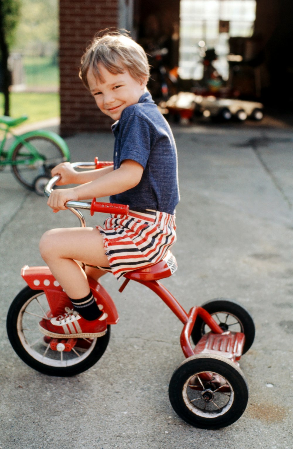 boy in blue and red crew neck t-shirt riding red trike