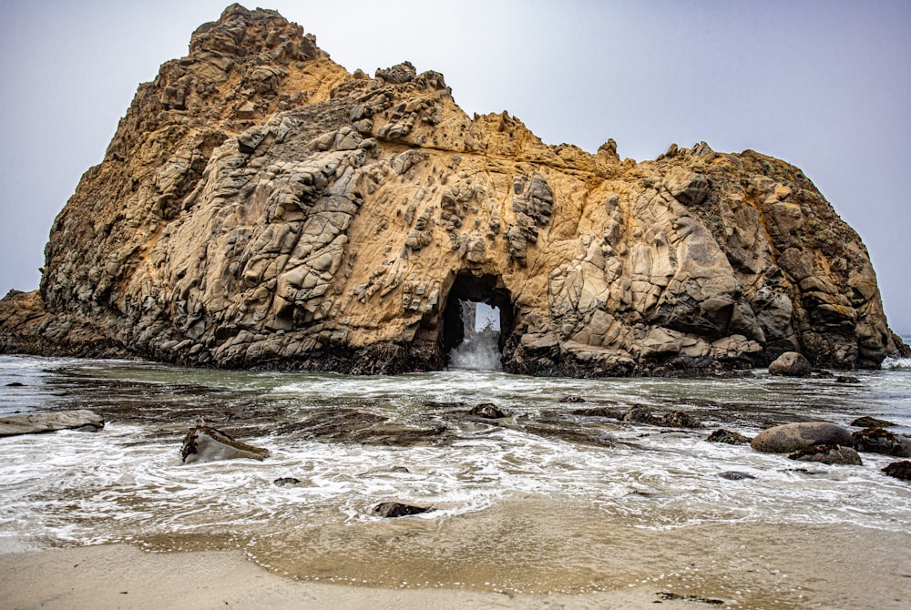 formação rochosa marrom na água do mar durante o dia