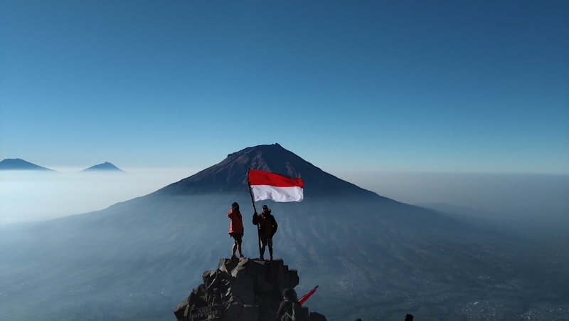 Pendaki berdiri di batu puncak gunung saat mendaki tektok pagi hari