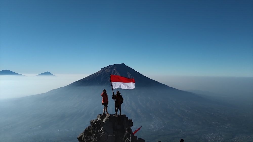 person standing on rock near mountain under blue sky during daytime