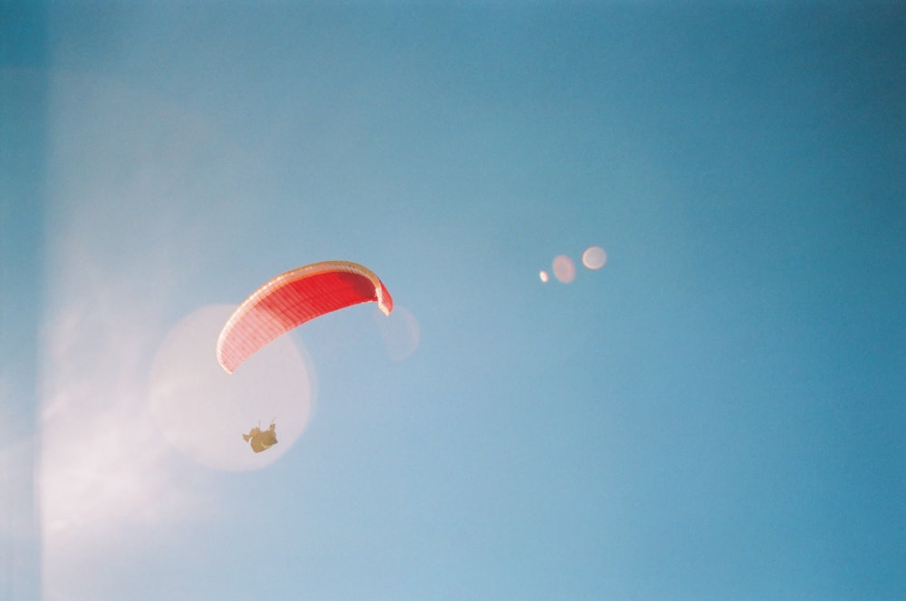 red and white parachute under blue sky