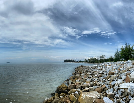brown rocks near body of water under blue sky during daytime in Ujong Permatang Malaysia
