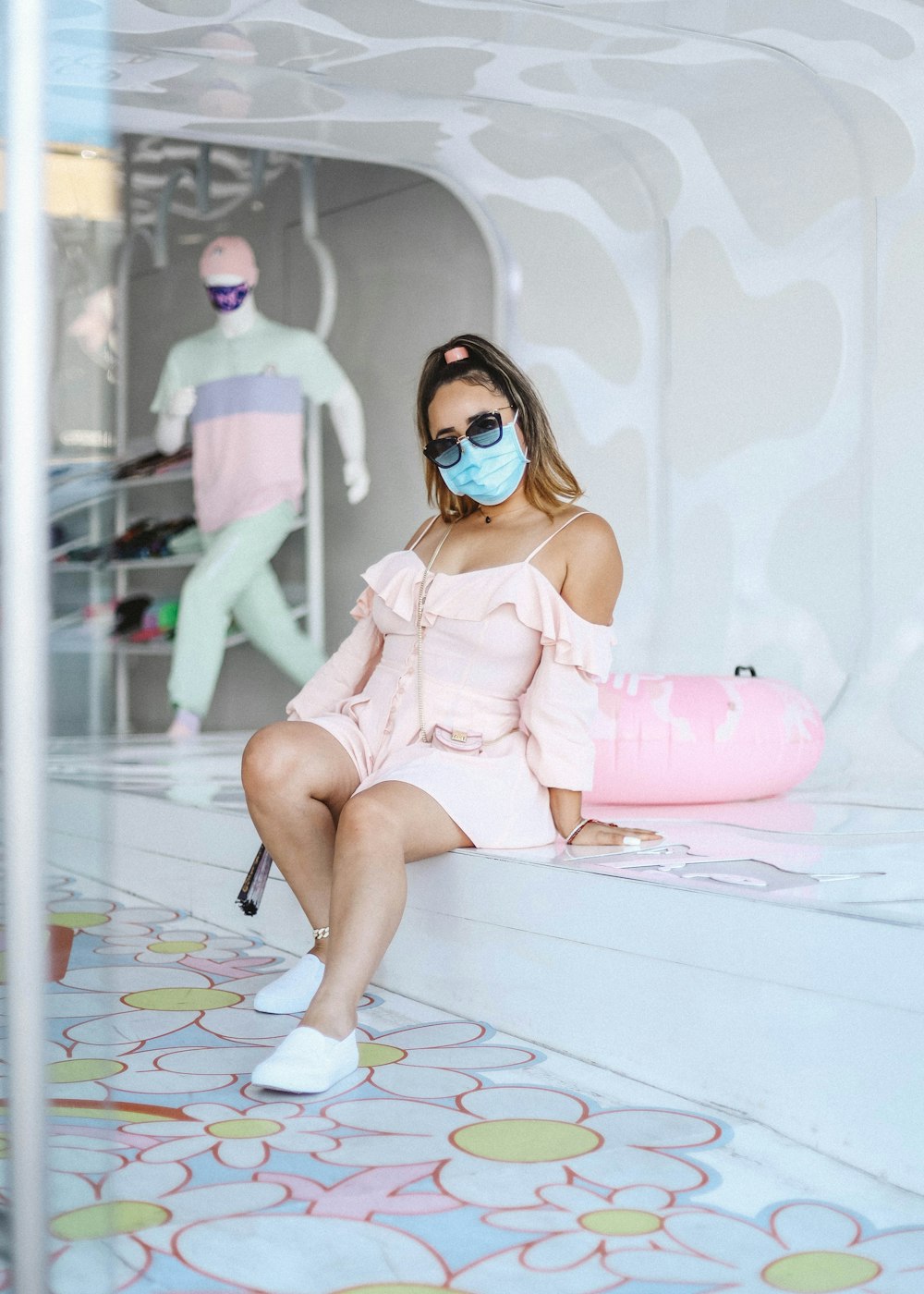 woman in pink dress wearing black sunglasses sitting on white floor