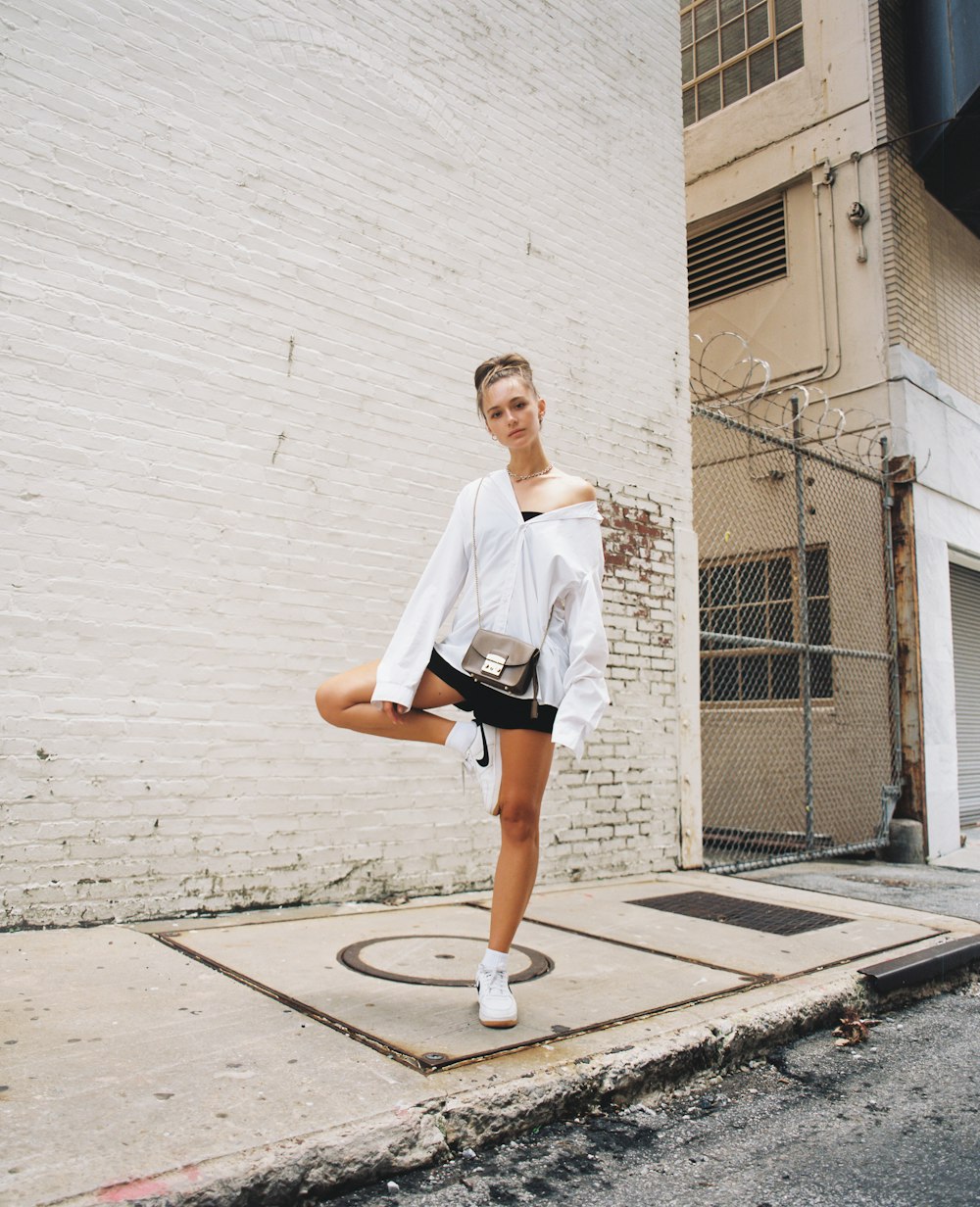 woman in white t-shirt and black shorts standing on gray concrete floor during daytime