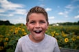 boy in white crew neck shirt standing on yellow flower field during daytime