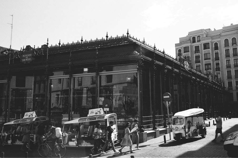 grayscale photo of people walking on street near building