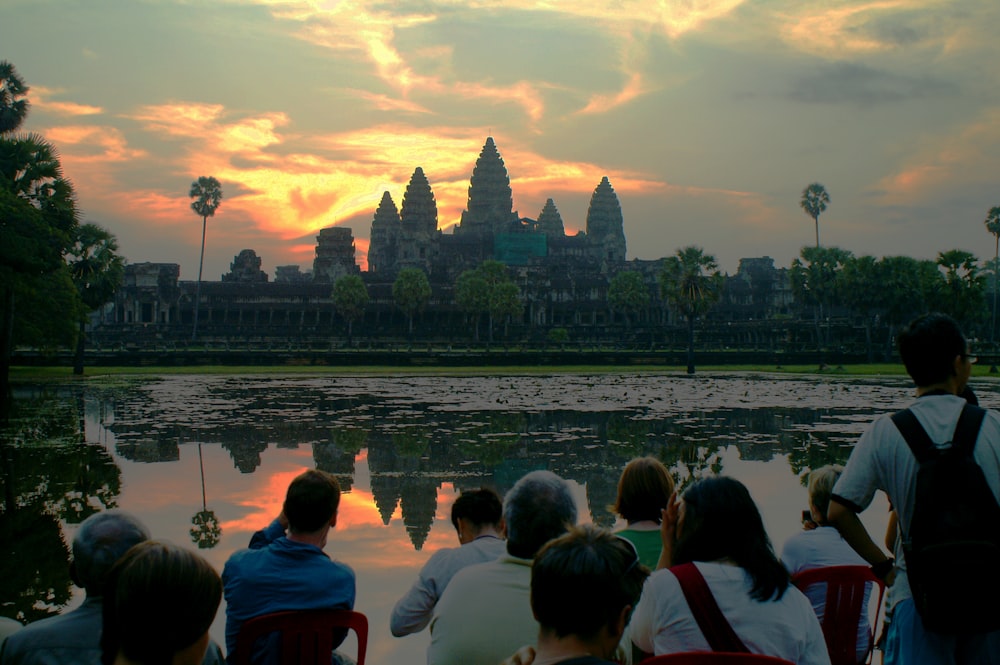 people sitting on the ground near body of water during daytime