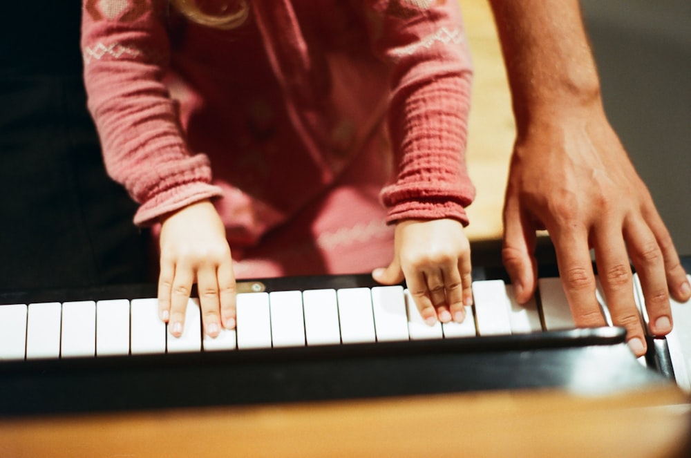 person in red long sleeve shirt playing piano