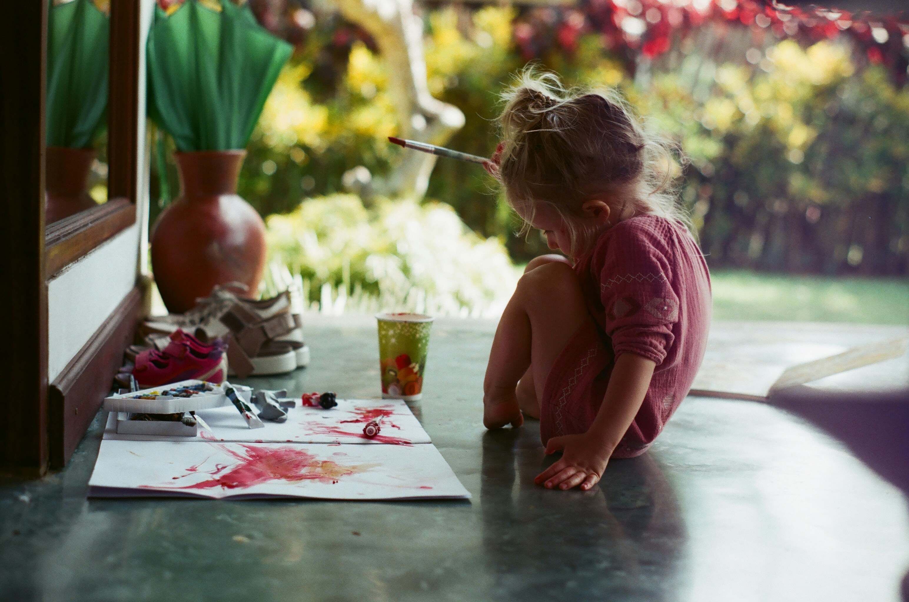 girl in pink shirt sitting on floor while writing