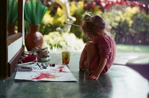 girl in pink shirt sitting on floor while writing
