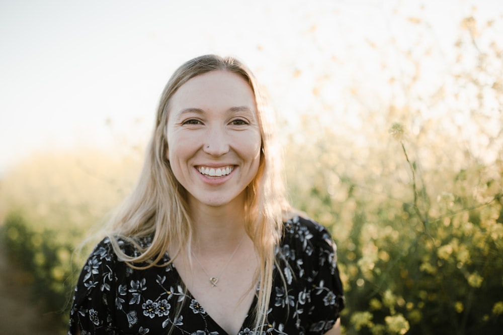 smiling woman in black and white floral shirt