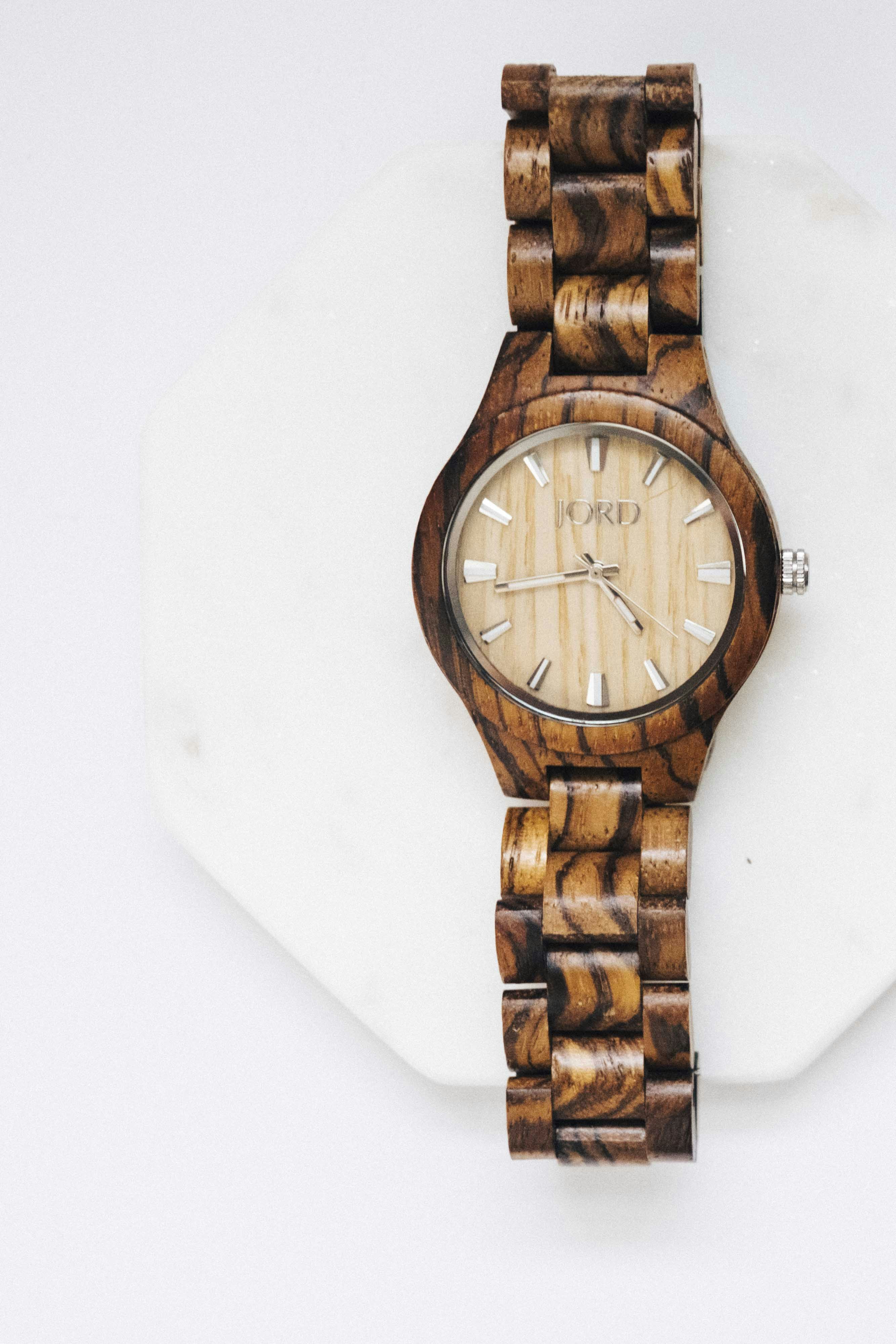 Elegant wooden wristwatch on a clean white surface with natural wood grain visible